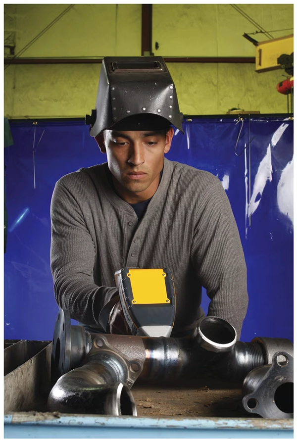 Worker using Niton XRF analyzer on metal pipes